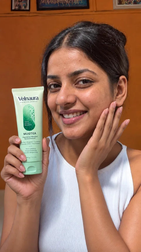 A smiling woman holds Mugtea beside her face in warm light.