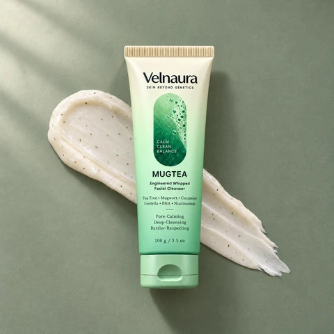 A Velnaura Mugtea tube rests vertically over an ivory cleanser swipe on a sage surface.